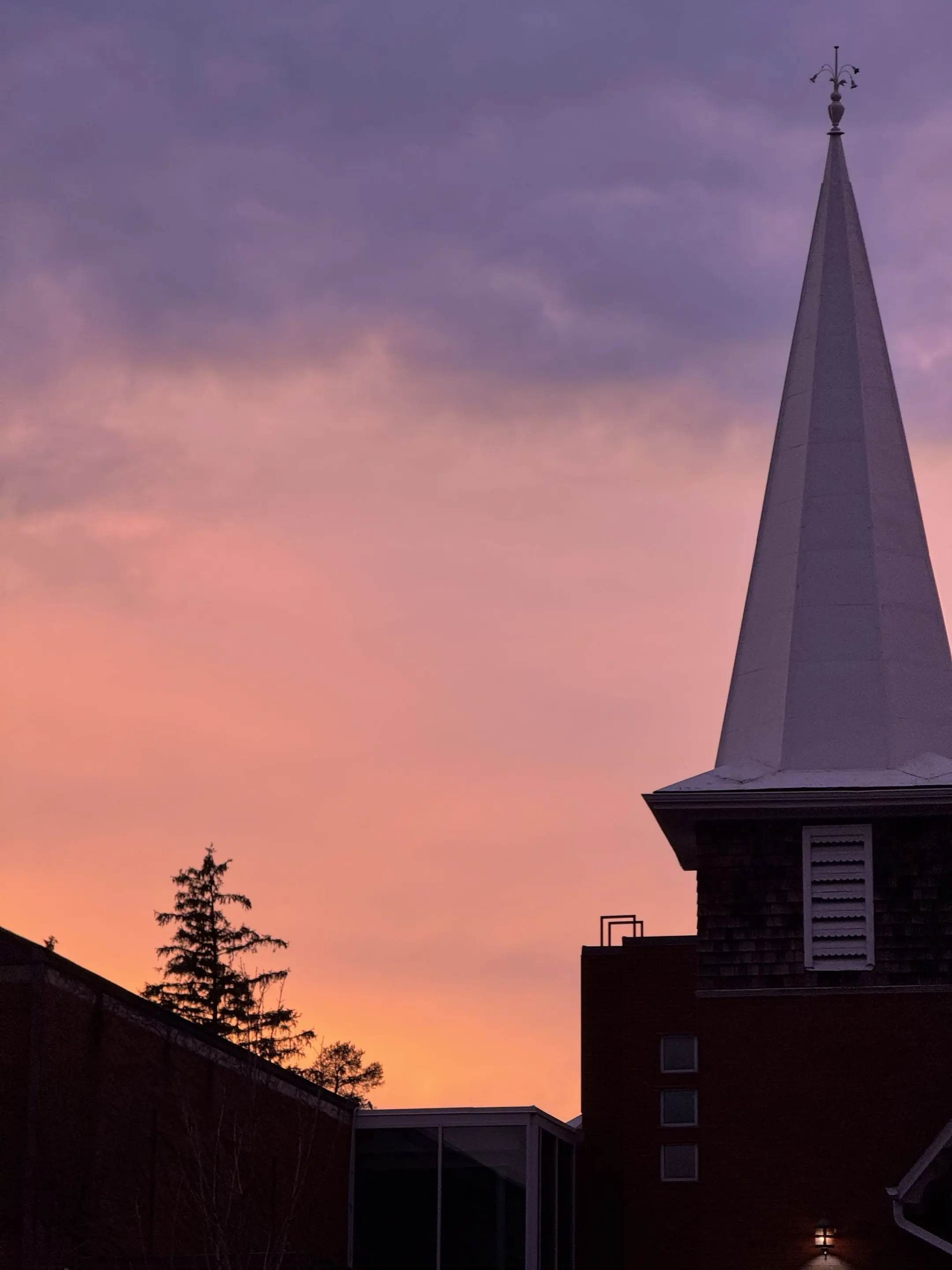 A church silhouetted beneath a pink-and-purple sunset sky.